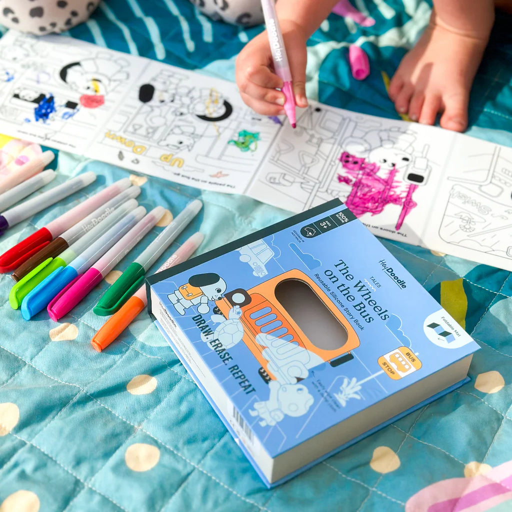 Children's coloring book with markers on a blue blanket