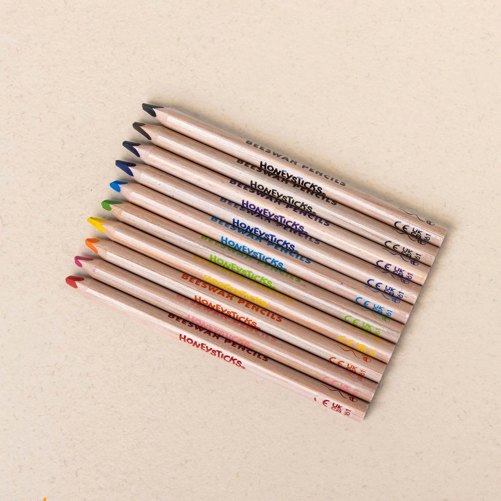 Set of colored pencils with visible brand names on a beige background