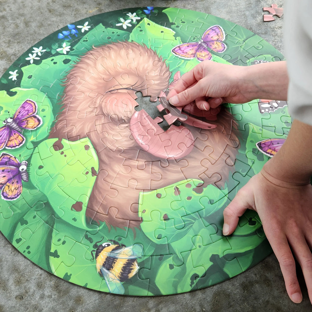 Person assembling a puzzle of a kiwi with a green background featuring butterflies and flowers.