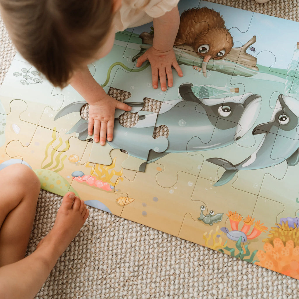 Child playing with a puzzle featuring sea creatures on a carpeted floor.