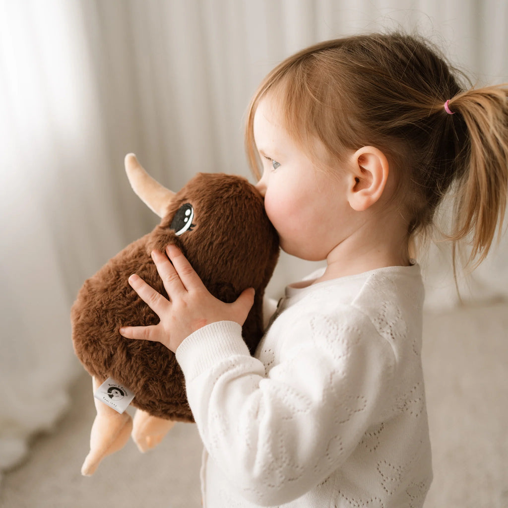 Child holding a brown plush toy against a neutral background
