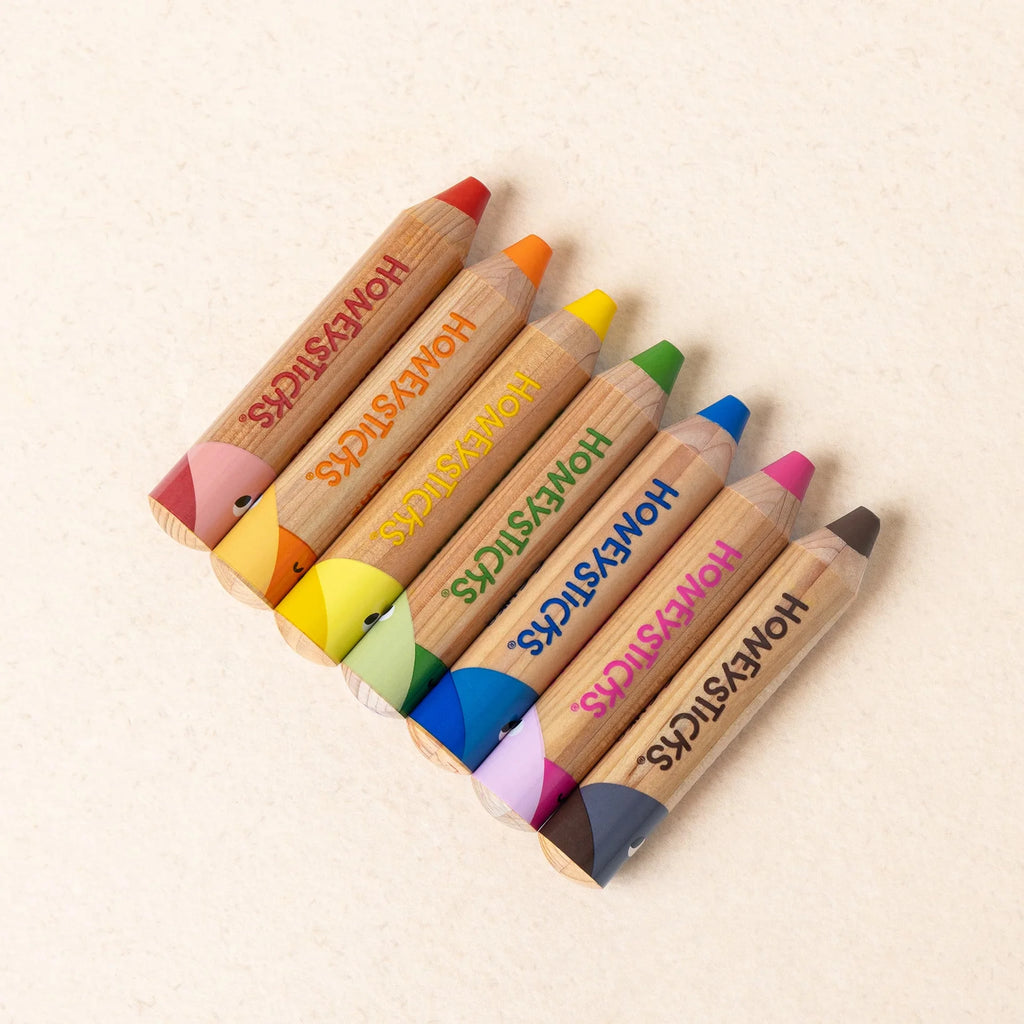 Set of colorful lip pencils with 'Honeysticks' branding on a beige background