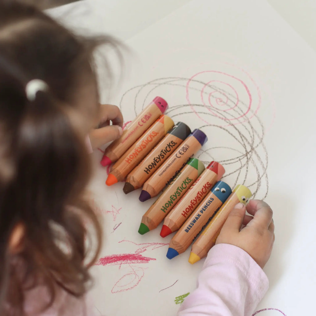 Child drawing with colorful crayons on a piece of paper