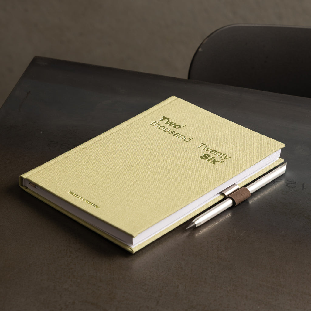 green notebook with a pen on a dark surface