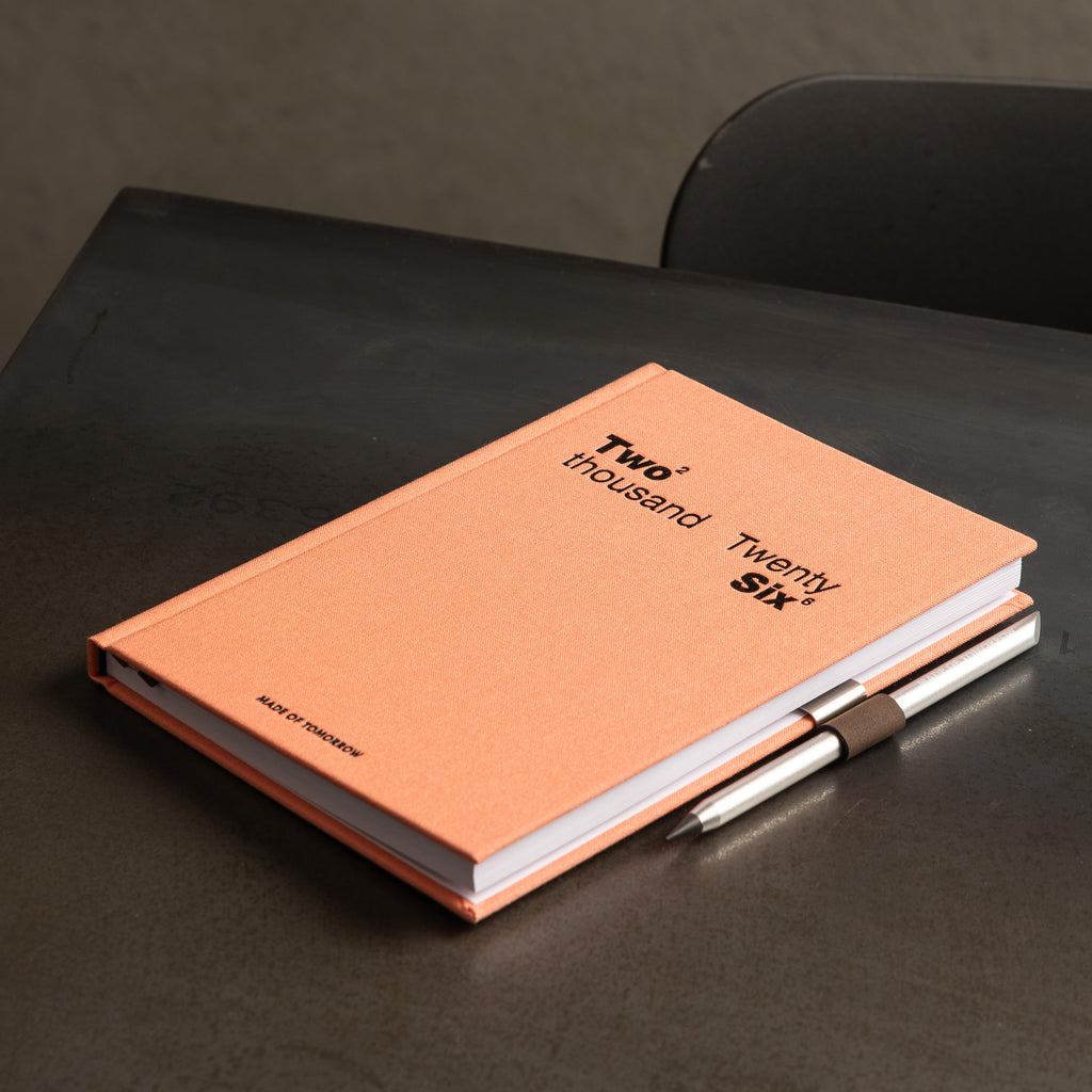 Orange notebook with a pen on a dark surface