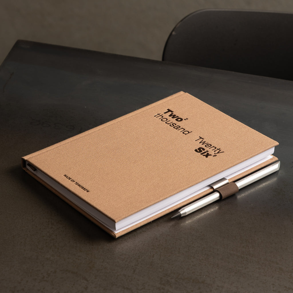 Brown diary with a pen on a dark surface