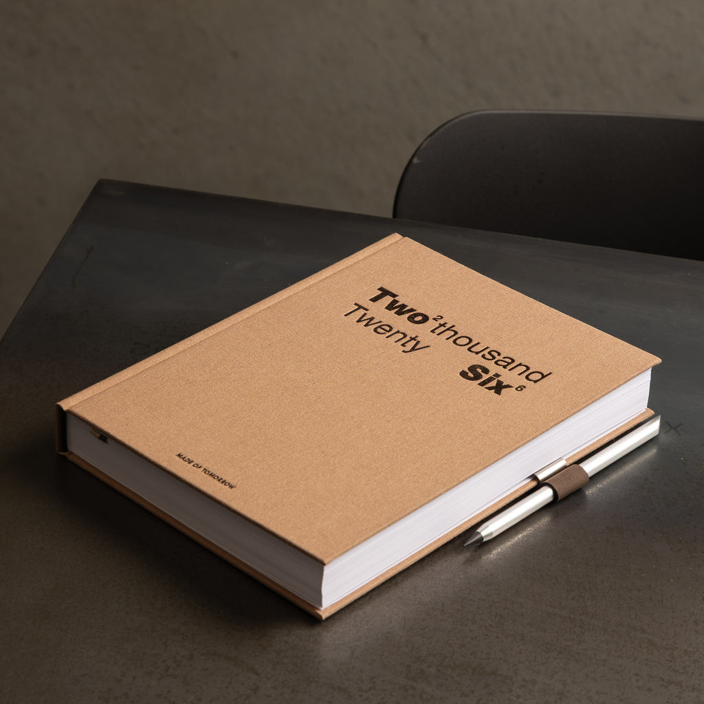 Brown notebook with 'Two thousand Twenty Six' on a dark surface