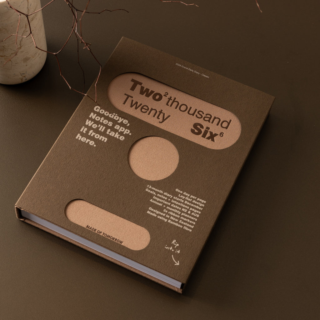 Brown book with 'Two thousand Twenty Six' design on a dark surface