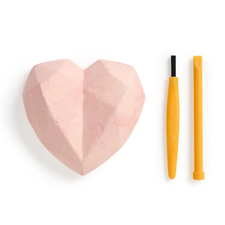 Heart-shaped pink object with two yellow sticks on a white background