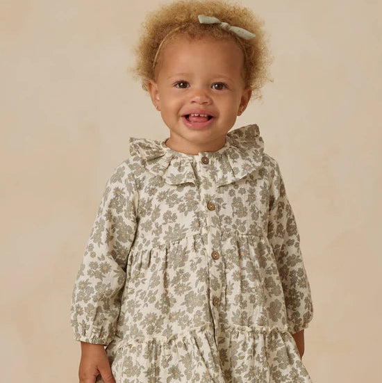 Child wearing a floral dress with a bow on a beige background