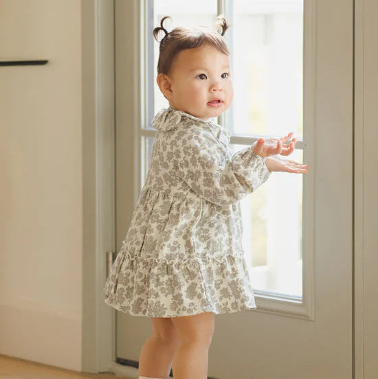 Child in a floral dress standing by a door