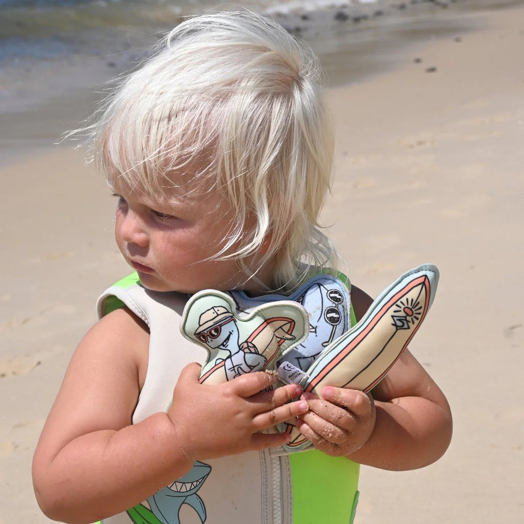 Child holding colorful toys on a beach