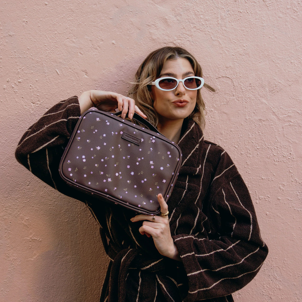 Woman holding a brown bag with star patterns against a pink wall