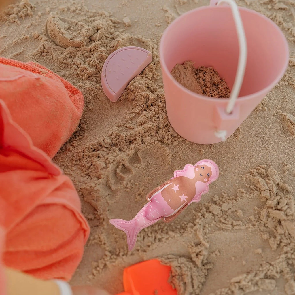 Pink sand toy with mermaid design on a sandy surface