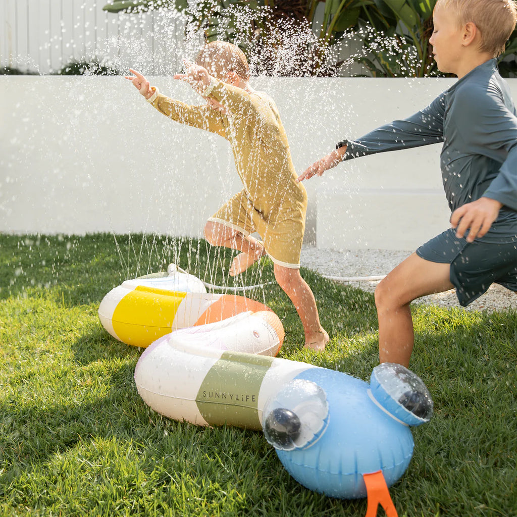 Two children playing with a colorful inflatable toy on grass