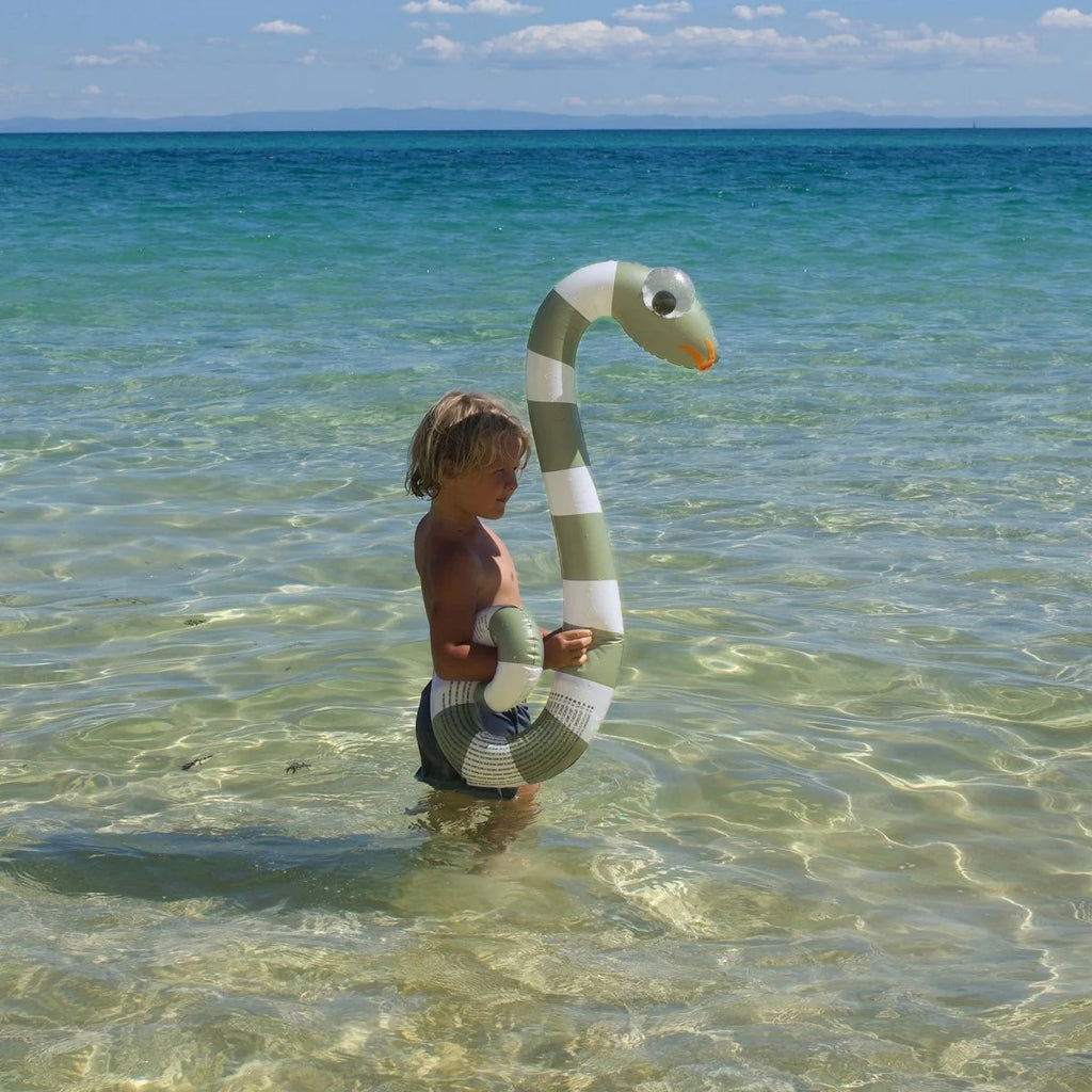 Child holding an inflatable snake toy in clear ocean water