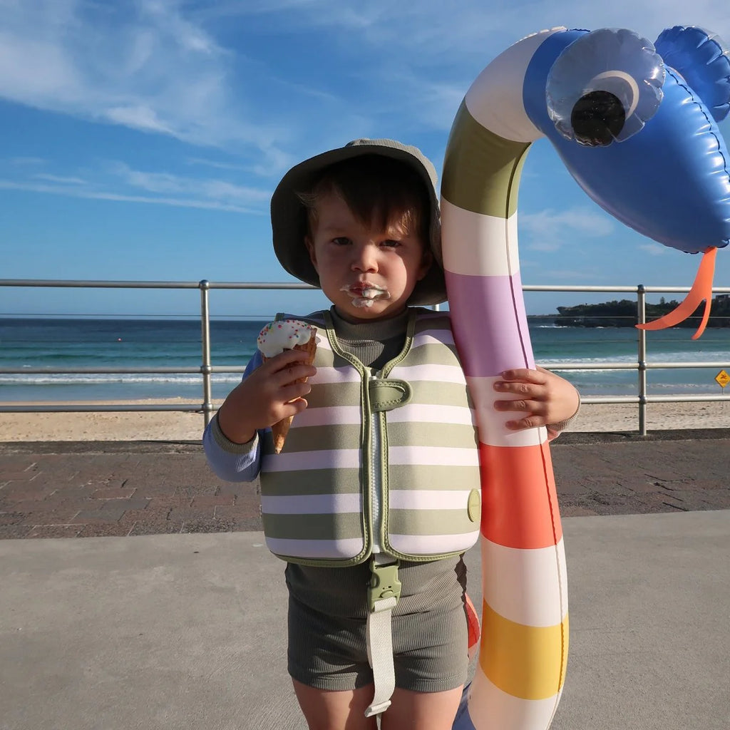 Child holding an inflatable sea creature by the beach