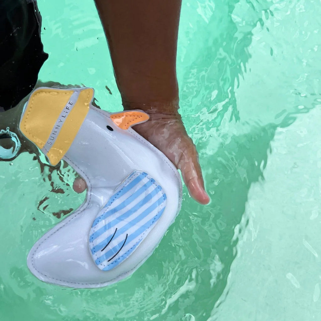 Child's hand holding a seagull-themed pool toy with  a hat on