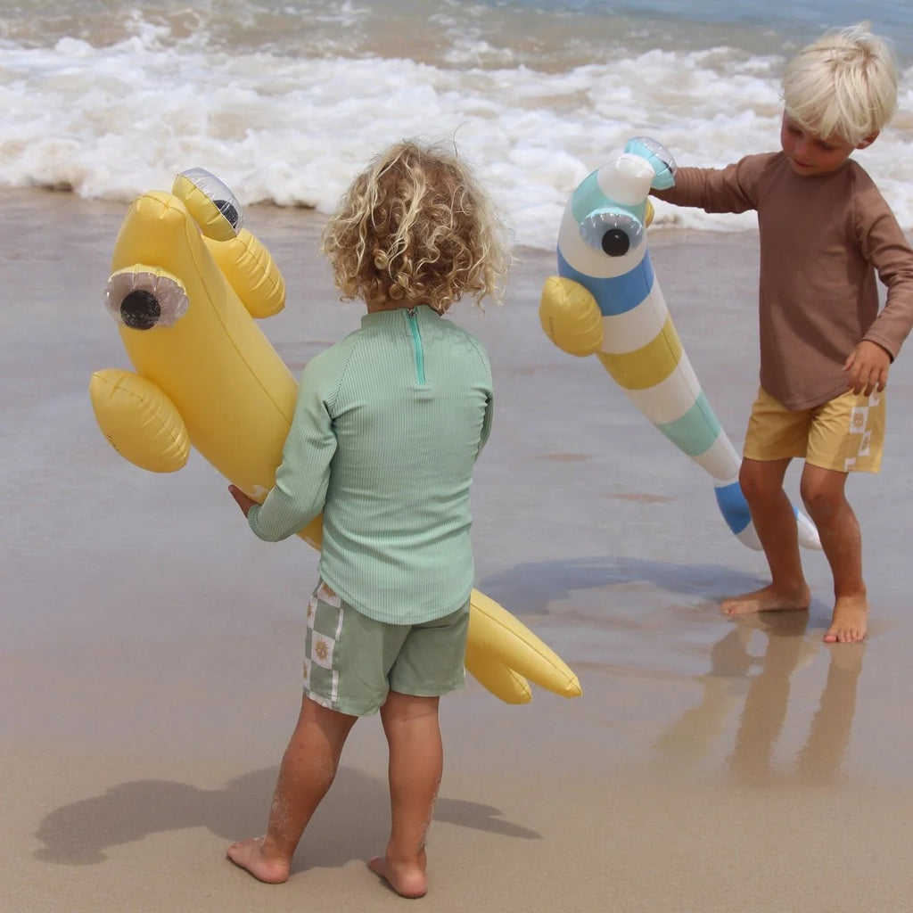 Two children playing on a beach with inflatable sea creature toys.