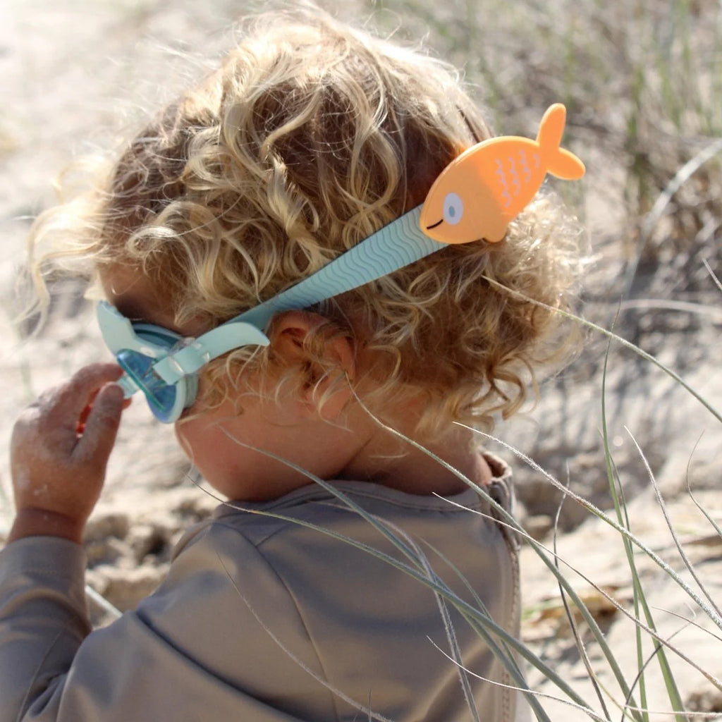 Child wearing a snorkel with a fish design on a beach