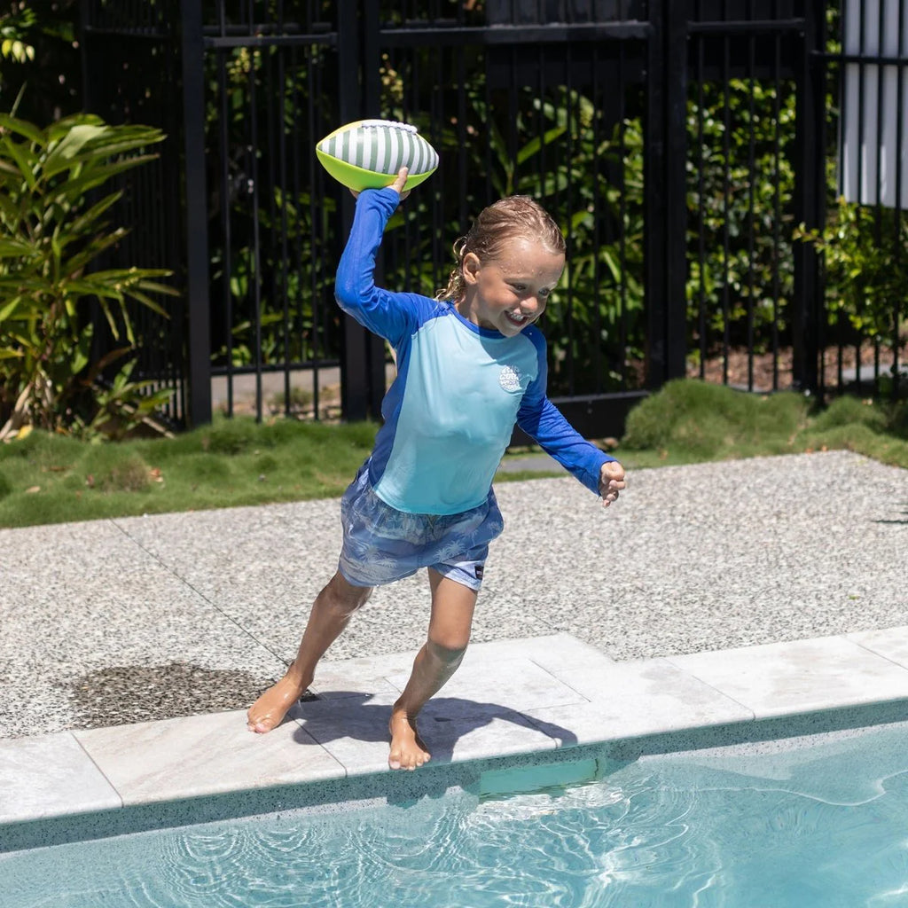 Child playing with a football by a pool