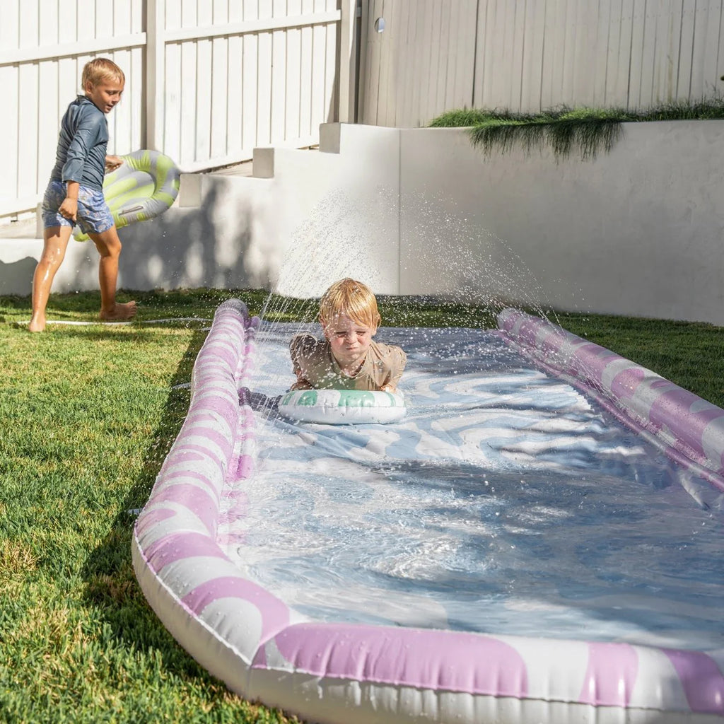 Children playing with an inflatable slide in a backyard.