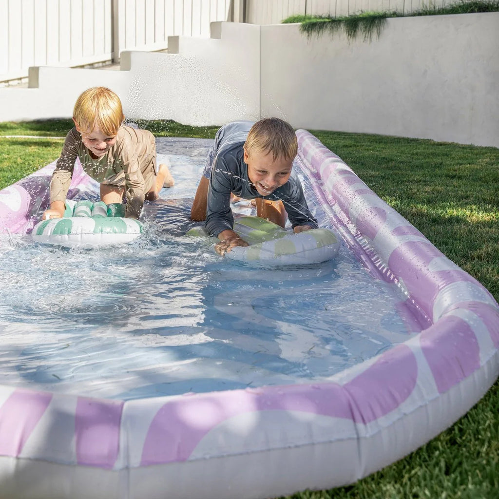 Two children playing in a small inflatable slideoutdoors.