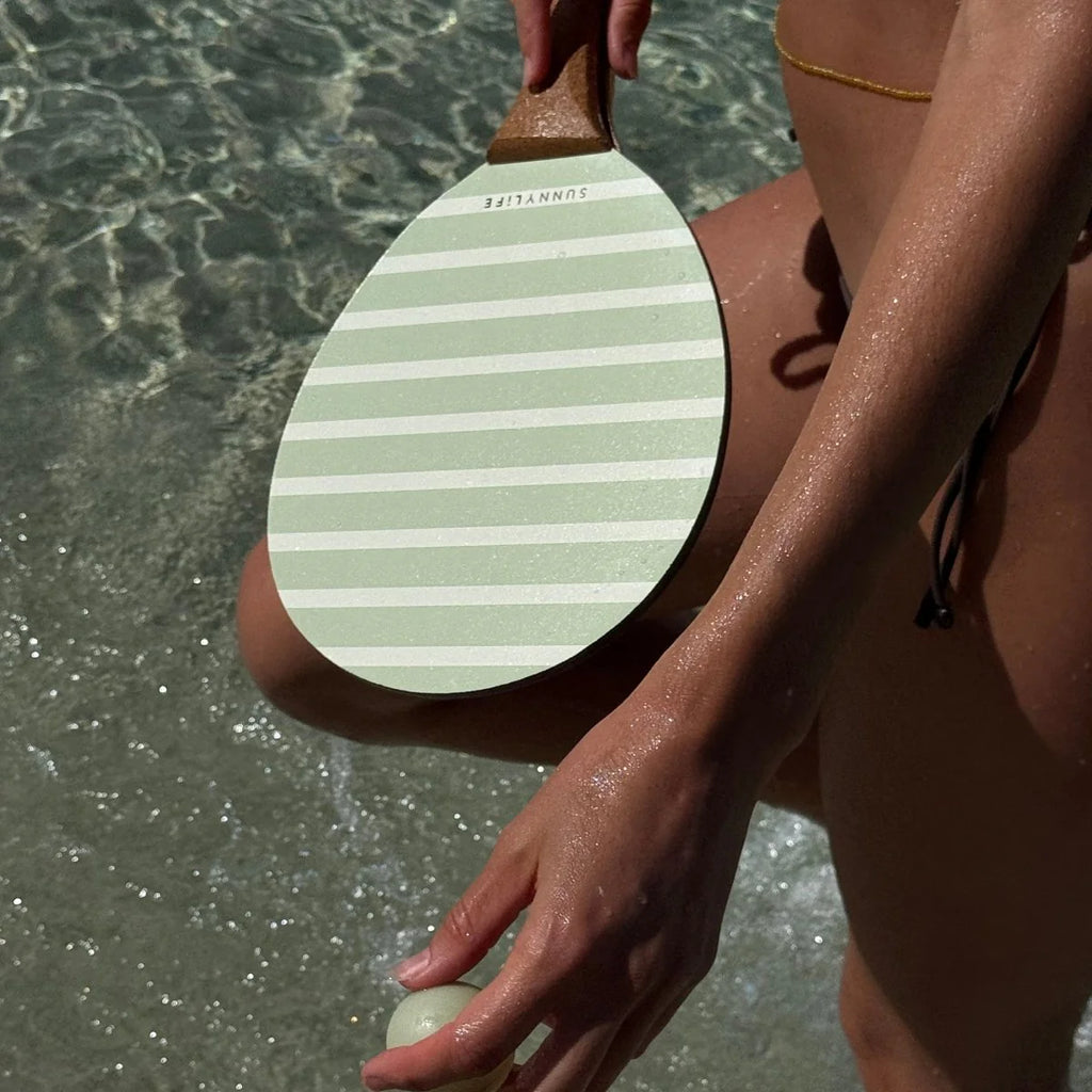Person holding a striped paddle by the water
