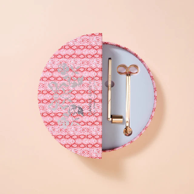 Round candle care set with pink and white patterned case on a beige background