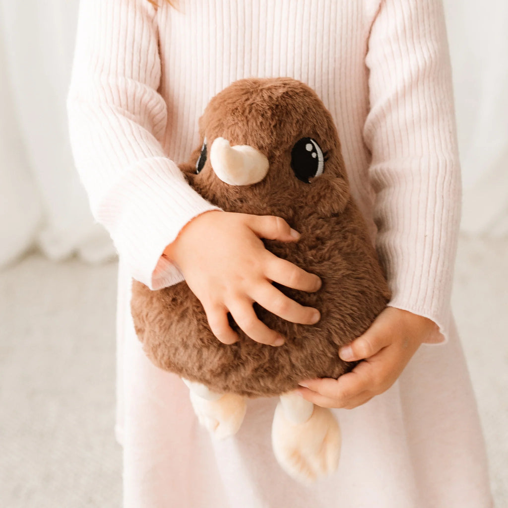 Person holding a brown plush toy with large black eyes and a white nose.
