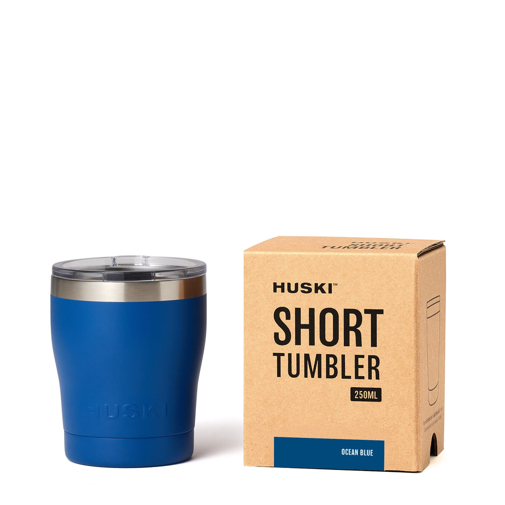 Blue tumbler with Huski branding next to its packaging box on a white background