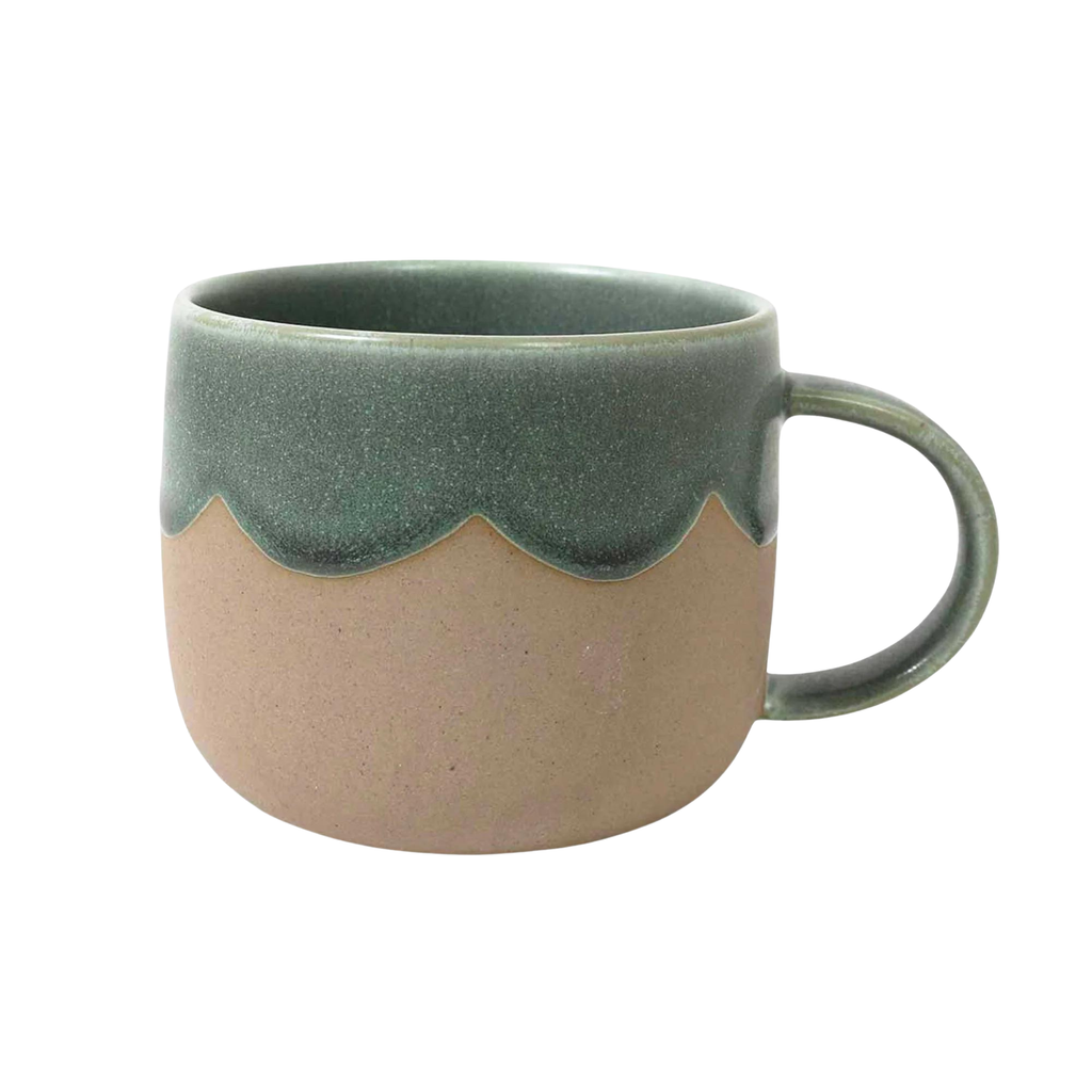 A brown ceramic mug with a dipped edge and inner with green glaze and a scalloped edge against a white background  