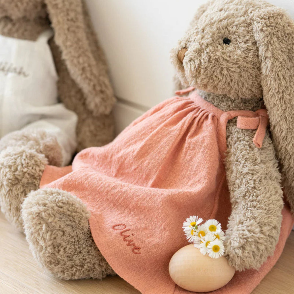 Soft toy bunny wearing a pink dress with the name olive on it