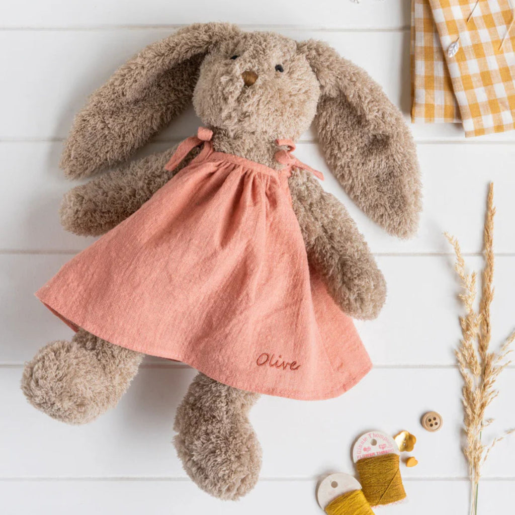 Soft toy bunny wearing a pink dress with the name olive on it