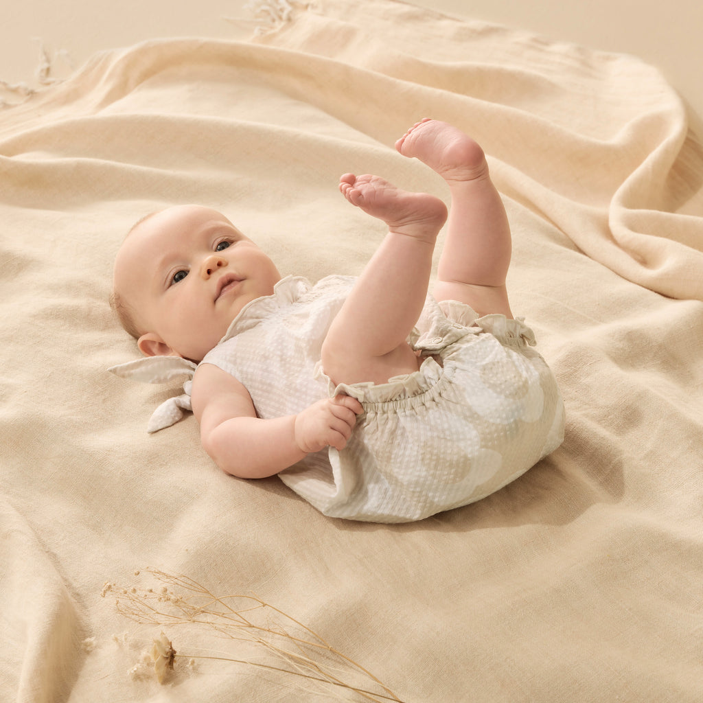 Baby lying on a beige blanket with a soft focus background