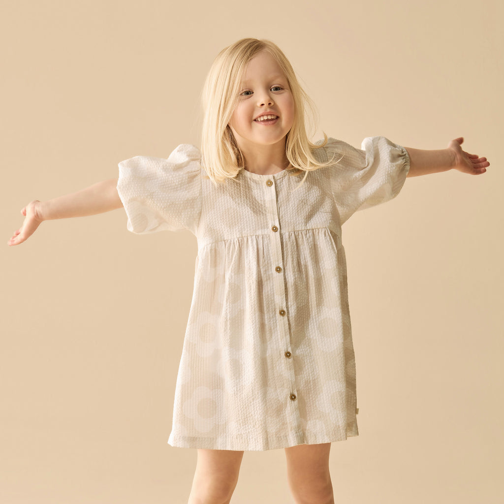 Young girl wearing a white dress with puffed sleeves on a beige background