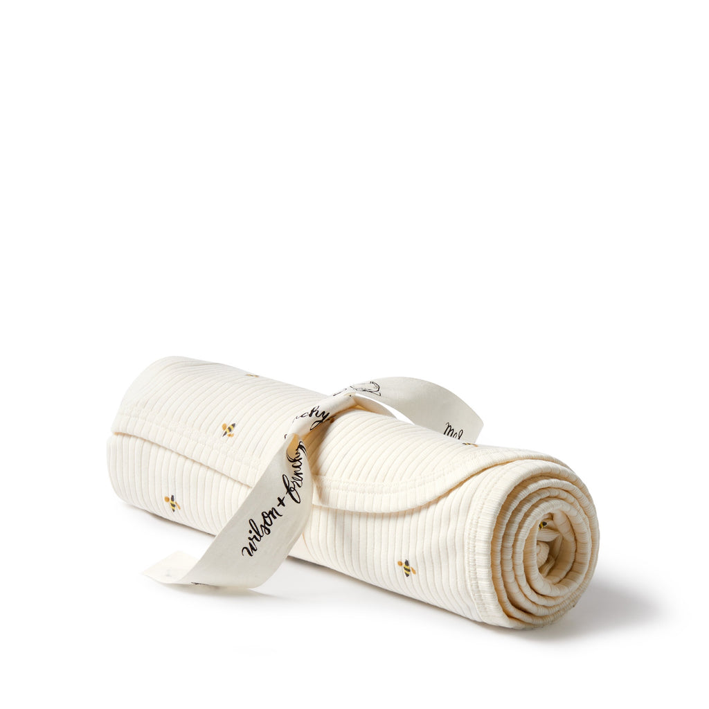 Rolled-up white blanket with a visible brand tag on a white background