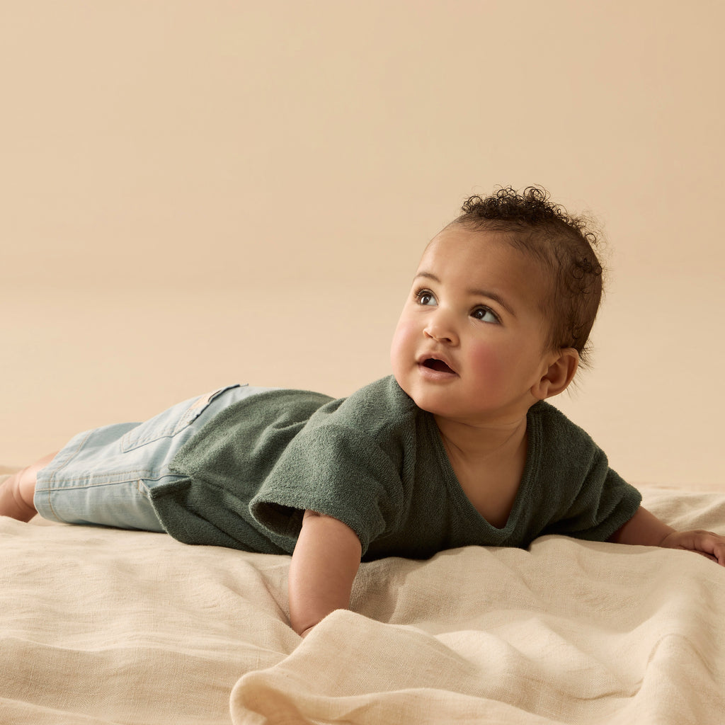 Baby lying on a beige blanket against a beige background