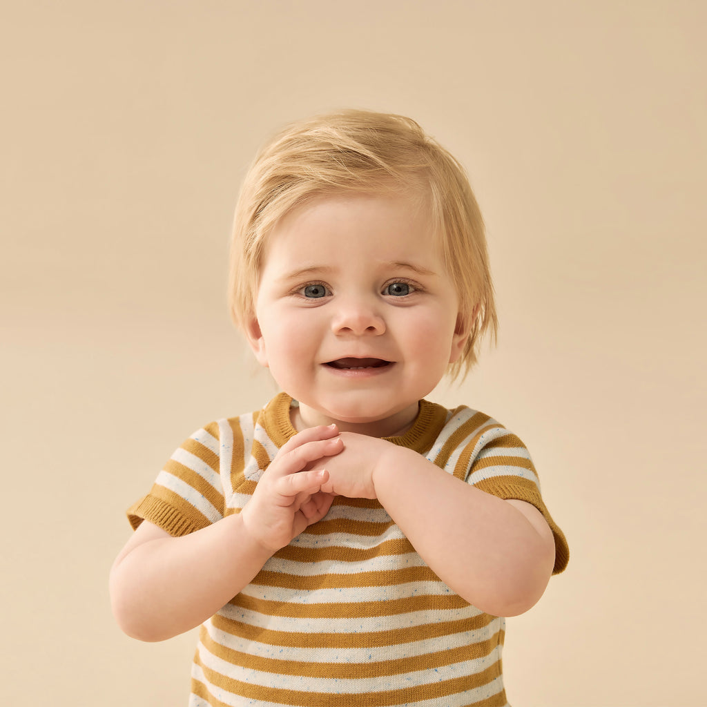 Child wearing a striped shirt against a beige background