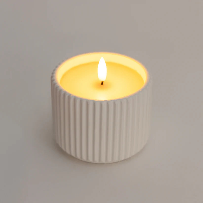 Candle in a ribbed container on a plain background