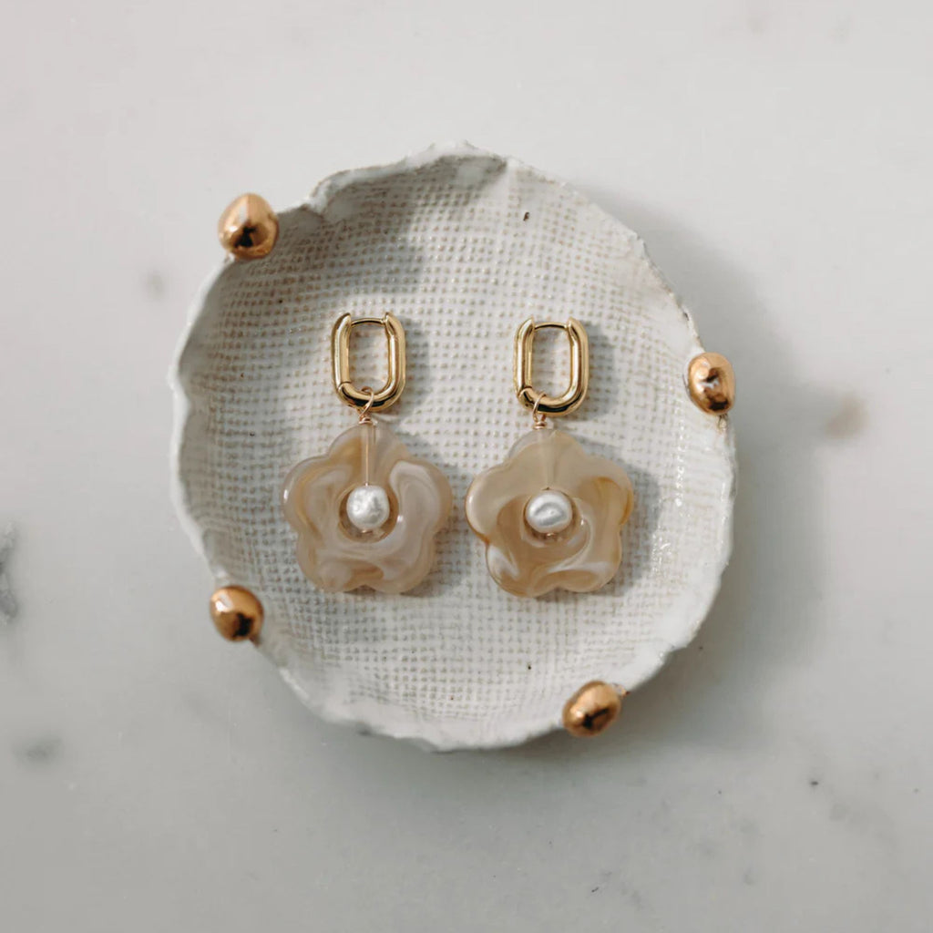 Pair of earrings on a textured white surface with a marble background