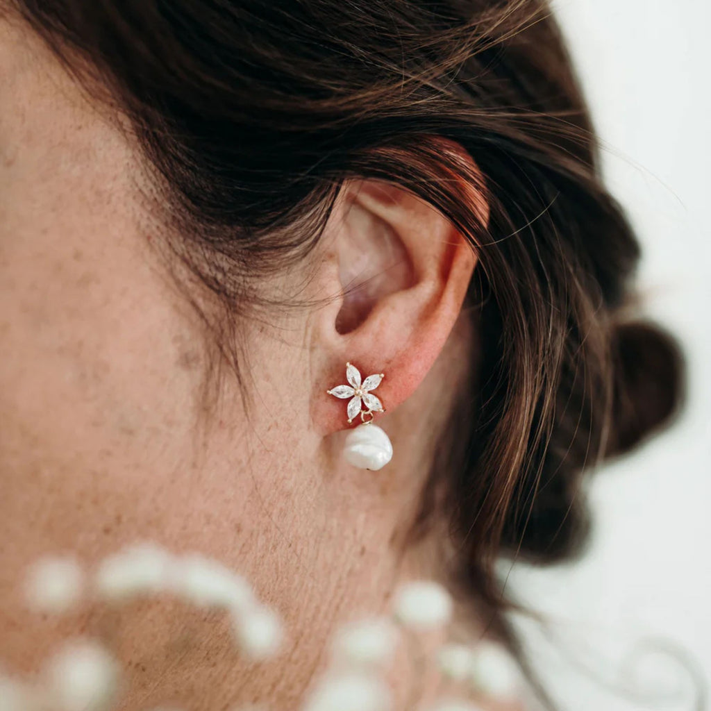 Close-up of an ear wearing a floral earring with a blurred background