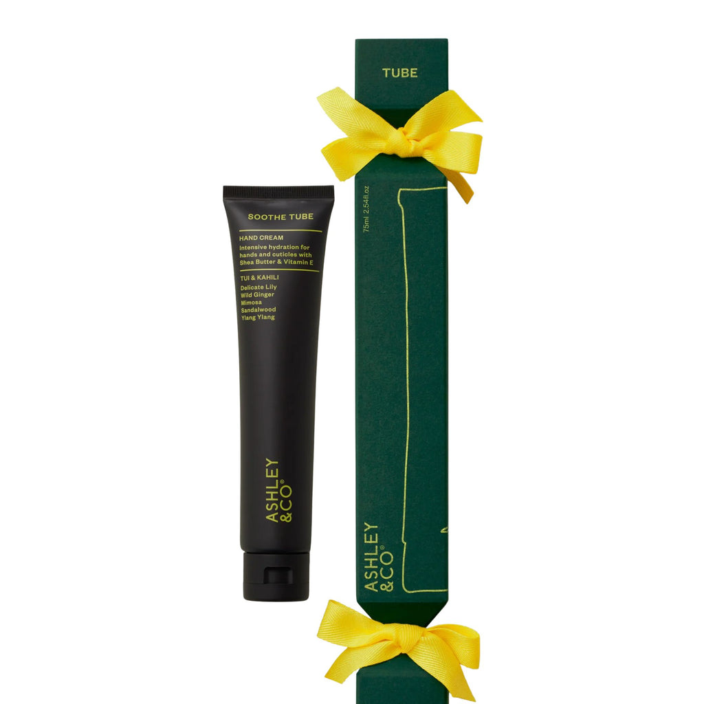 Tube of cream with green Christmas cracker packaging and yellow ribbon on a white background