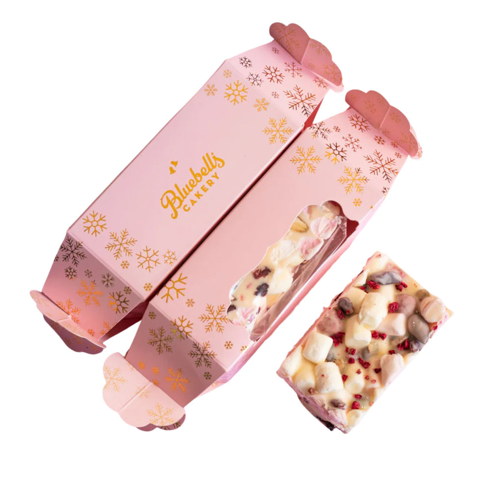 Pink gift box with snowflake patterns containing a chocolate bar, branded 'Bluebells Cakes'.