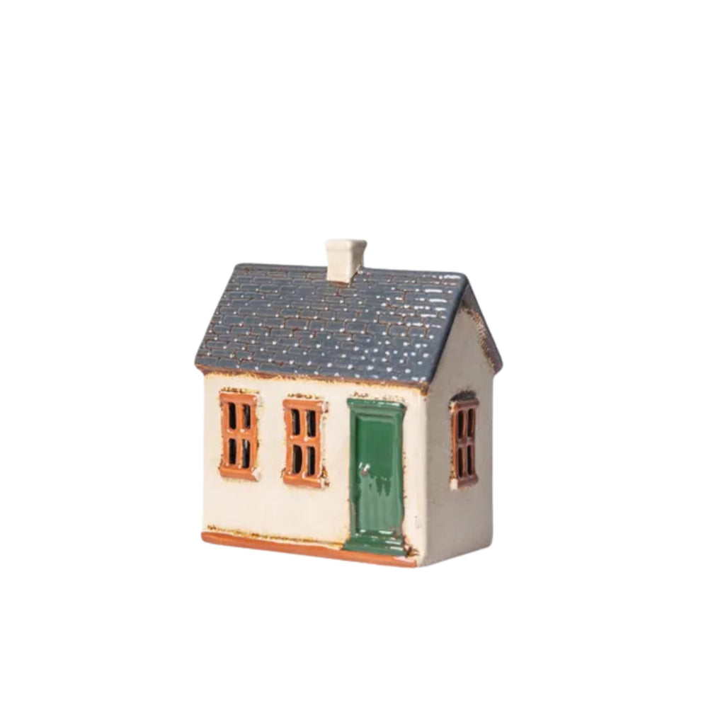 Small ceramic model of a house with a green door on a white background