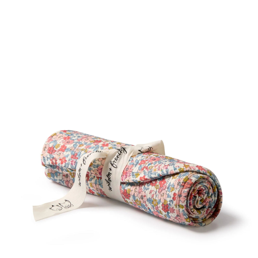 Rolled-up floral fabric with a visible brand label on a white background