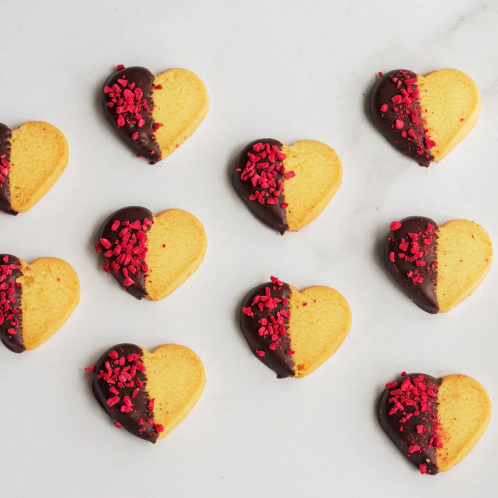 Heart-shaped cookies with chocolate and red sprinkles on a light background