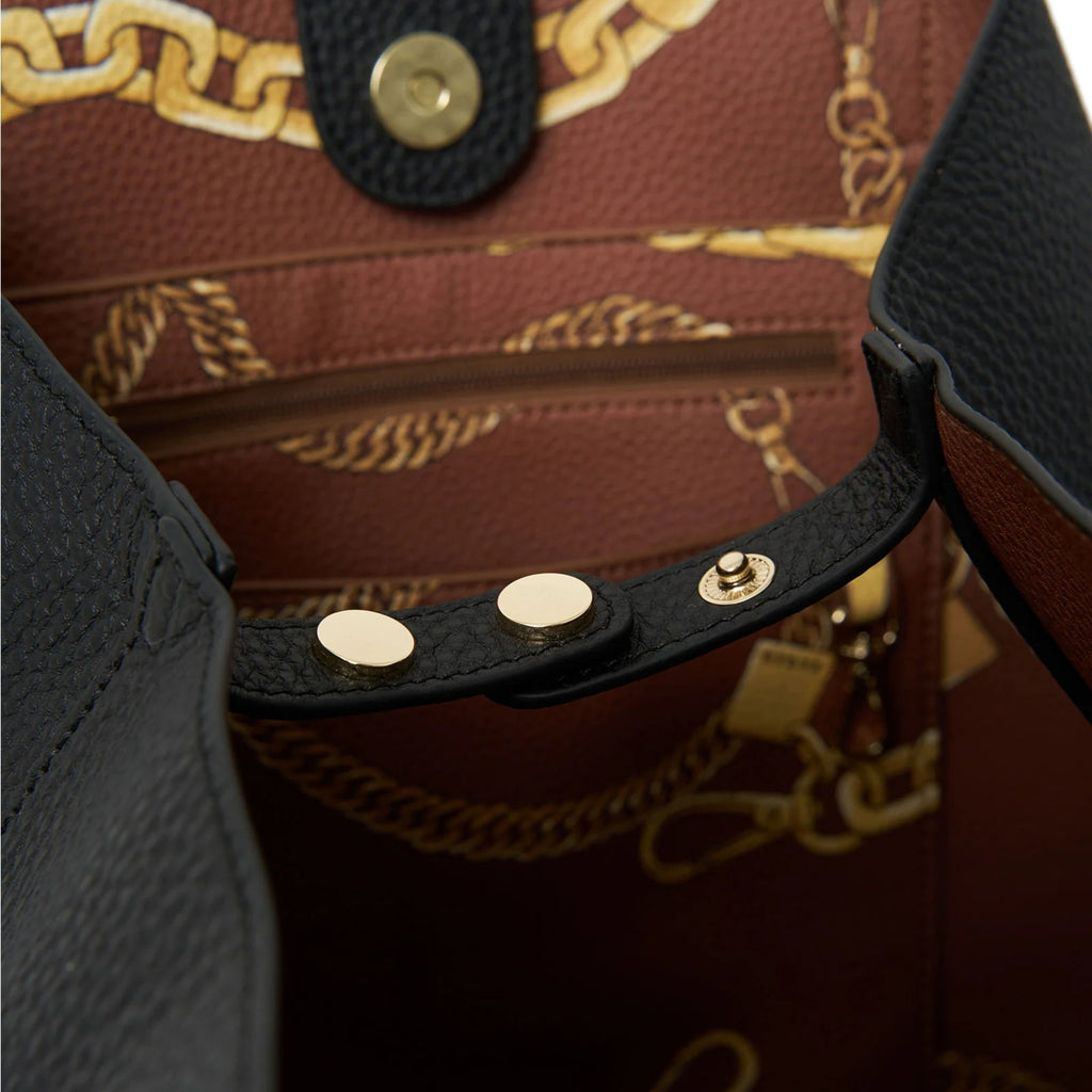 A bag interior with a brown leather and gold chain pattern with a black clip bag