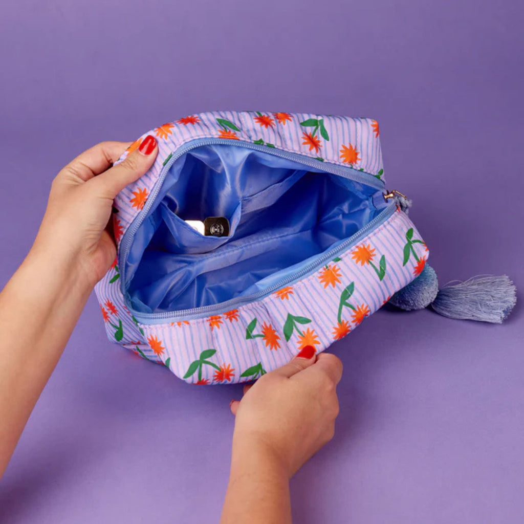 Floral-patterned pouch with a blue interior on a purple background