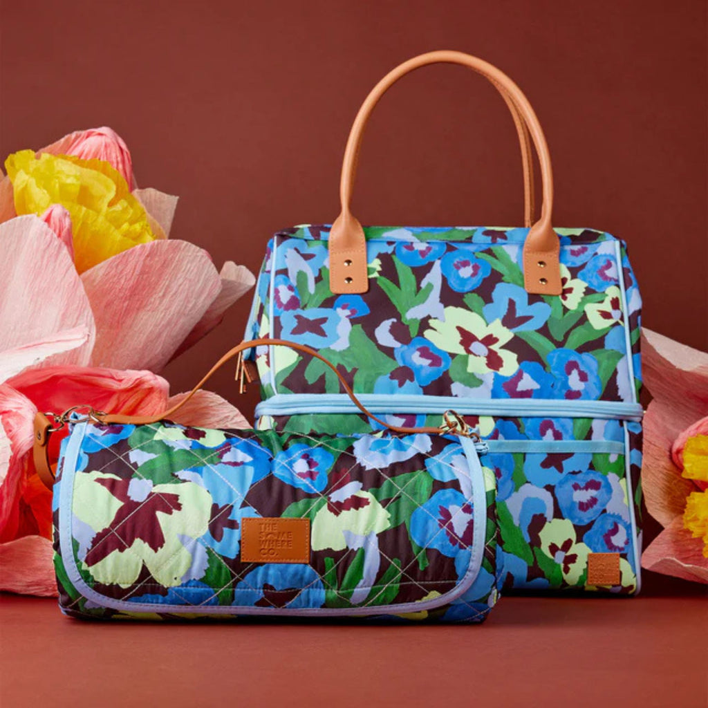 Colorful floral-patterned handbag and pouch with a brown handle on a red background.